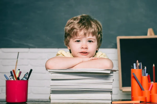 Hem- eller skolutbildning. Porträttbarn från grundskolan. Grabben med en bok. Kalkbrädans kopieringsutrymme. Söt pojke i klassrummet nära skrivbordet. — Stockfoto