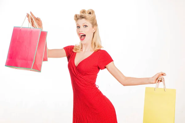 Portret vrouw in pin-up stijl rode jurk met winkeltassen. Verkoop, consument, retro mode. Mooie blonde vrouw in rode jurk met retro kapsel. — Stockfoto