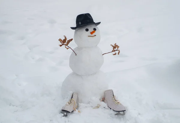 Il pupazzo di neve indossa un cappello di pelliccia e una sciarpa. Carino pupazzo di neve in cappello e sciarpa sul campo innevato. Nuovo concetto di anno. Natale pupazzo di neve su sfondo bianco neve — Foto Stock