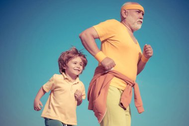 Aile için koşu ve maraton koşusu. Büyükbaba ve çocuk sporcular dışarıda koşuyor ve güneşli günün tadını çıkarıyorlar. Büyükbaba ve torun dışarıda spor yapıyor. Sağlıklı, genç bir yaşam tarzı..