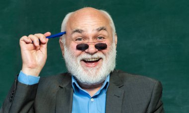 Karatahta masasının yanındaki sınıfta dost canlısı bir öğretmen. Eğitim ve öğrenim insanları kavramı - kadın öğretmen tahtaya yakın. Öğretmenler günü. Teşekkürler öğretmenim..