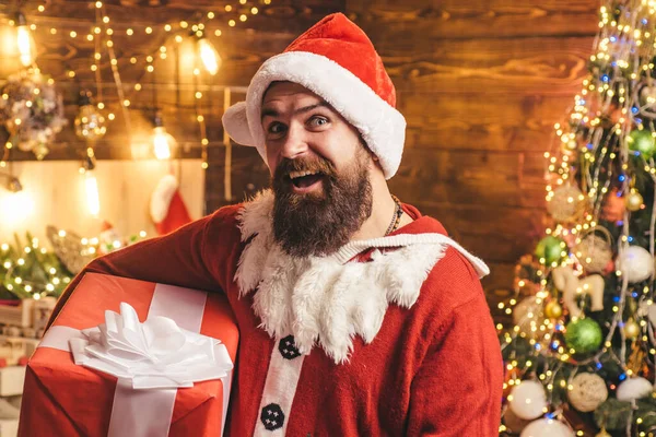 Noel Baba 'nın hediyesi. Hippi, sakallı Noel Baba Şükran Günü 'nü ve Noel' i kutluyor. Kırmızı Noel Baba şapkalı hippi hediyesini tutuyor.. — Stok fotoğraf