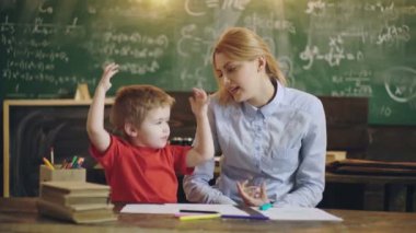 İlkokul. Anaokulu çocuğu. Sınıfta bir öğretmenle ders çalışan sevimli bir çocuk..