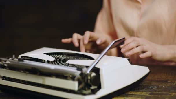 Handen typen op een typemachine. Close up van typemachine met wit blanco vel papier met vrouwelijke hand typen. — Stockvideo