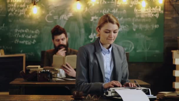 Professor and secretary or assistant working at his desk with vintage typewriter front of a blackboard. — Stock Video