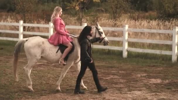 Pareja joven enamorada de montar a caballo. Pareja hombre y mujer caminando en un rancho con caballos. — Vídeo de stock