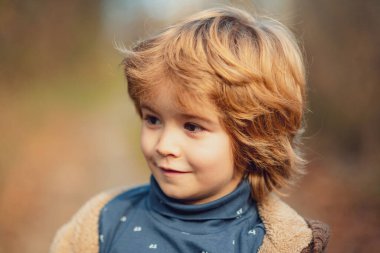 Parktaki çocukların sonbahar portresi. Güneşli bir günde gülümseyen çocuk.