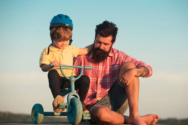 Papá ayuda a su hijo a montar en bicicleta. encantador padre enseñanza hijo montar en bicicleta. — Foto de Stock