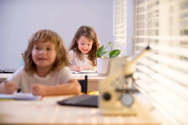 Dzieci siedzące przy biurku w klasie szkolnej i piszące test. Uczniowie piszący w notatniku podczas lekcji w klasie. — Zdjęcie stockowe