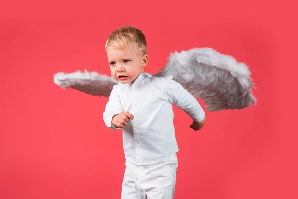 Drôle de Saint Valentin. Cupidon ange enfant avec des ailes est amusant, isolé sur rouge. — Photo