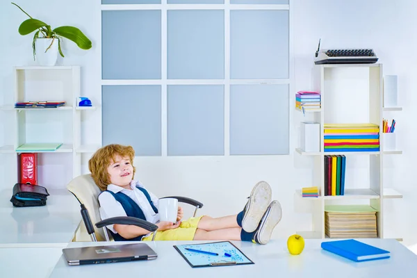 Petite carrière d'homme d'affaires d'enfant et concept de personnes. Homme d'affaires enfant a du succès commercial, avec succès au cas par cas. Garçon sérieux assis sur une chaise avec les jambes croisées levées sur la table. — Photo