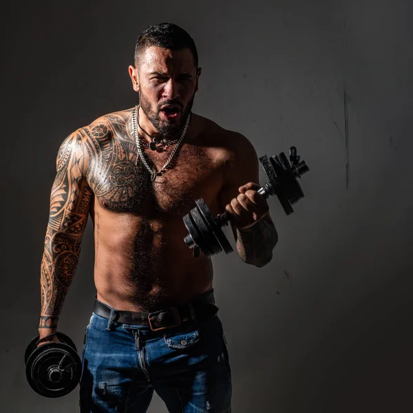 Homem musculoso sexy excitado com halteres. Homem atlético fazendo exercícios com halteres no bíceps. Homem desportivo com tronco nu. Força e motivação. — Fotografia de Stock