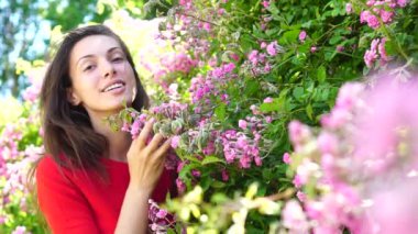 Bahar çiçeklerinde şehvetli bir kız. Güzel bir kadının açık hava portresi. Yavaş çekim, hareket.