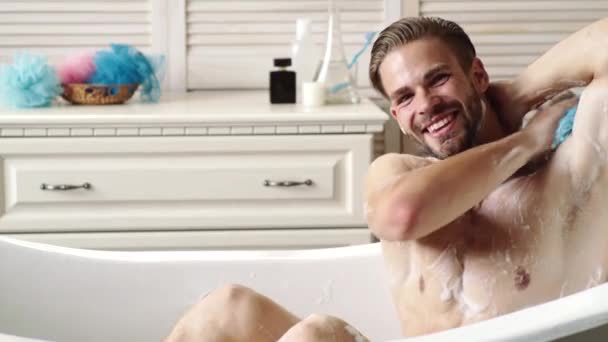 Ευτυχισμένος άνθρωπος με ξυράφι στο μπάνιο. Νεαρός χαμογελαστός τύπος στο εσωτερικό του μπάνιου. Έννοια της ανδρικής ομορφιάς, της φροντίδας του σώματος και της περιποίησης. — Αρχείο Βίντεο