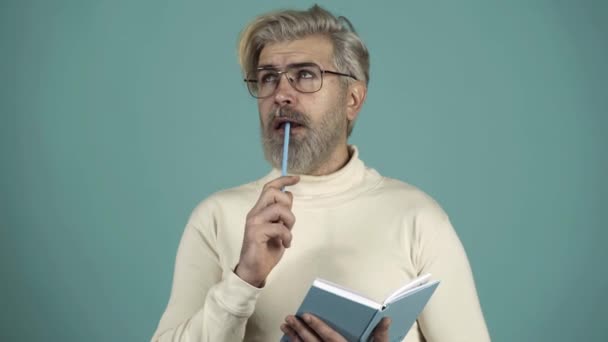 Writer thinker author journalist essay concept. Portrait of pensive intelligent handsome man imaging writing new project. Isolated on gray blue background. Funny positive man holding copybook. — Stock Footage Writer thinker author journalist essay concept. Portrait of pensive intelligent handsome man imaging writing new project. Isolated on gray blue background. Funny positive man holding copybook. Video Clip