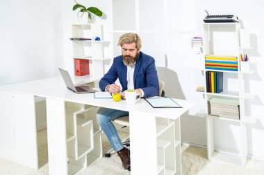 Genç girişimci bilgisayar kullanıyor. İnternette çalışan ekrana bakıyor. Ofis masasında oturuyor. Çalışanların iş yerindeki laptopta e-posta yazması.