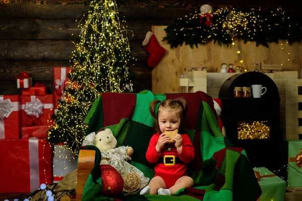 Kleines Baby mit Weihnachtsmütze isst Weihnachtsplätzchen. — Stockfoto