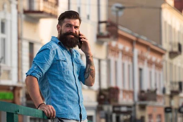 Un hombre de negocios sonriente hablando por teléfono en la ciudad. Hombre de negocios usando smartphone en la calle. Hombre parado fuera de un edificio. — Foto de Stock