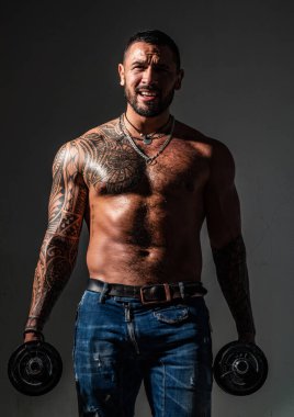 Güçlü yakışıklı sporcu halter kaldırıyor ve halterle kaslarını çalıştırıyor..