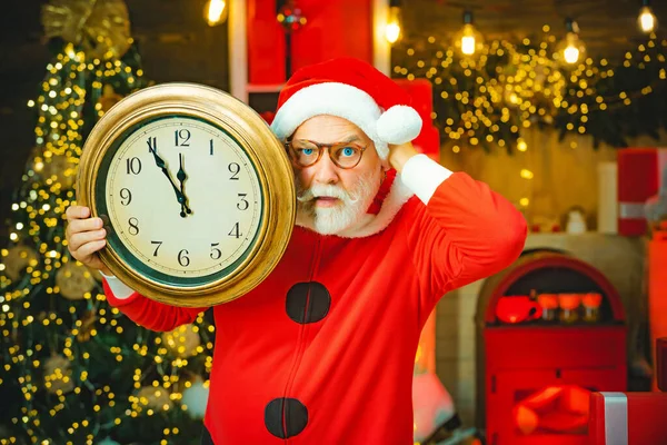 Fünf Minuten bis Silvester oder Weihnachten Mitternacht. Der Weihnachtsmann zeigt auf die Uhr. Weihnachtsmann. Der Weihnachtsmann zu Hause. Frohe Weihnachten Weihnachtsmann. — Stockfoto