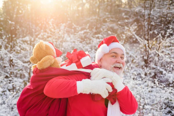 サンタの祖父は贈り物を届けます。雪の降る冬の山の中でクリスマスのスーツでサンタクロース。新年とクリスマスが近づいています. — ストック写真