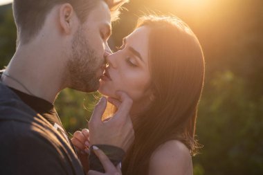 Sensual kiss. Young couple kissing and making love. Kisses lovers. Portrait of a beautiful young couple waiting to kiss against sunset light. clipart