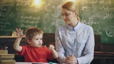 Okuldaki çocuk. Gülümseyen anne oğluna ev ödevinde yardım ediyor..