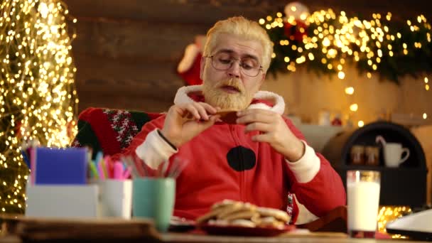 Vidám Mikulás tartja cookie közel kandalló és karácsonyfa. Mikulás vesz egy karácsonyi süti. — Stock videók