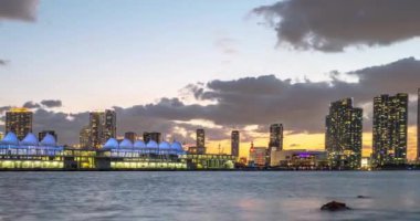 Miami, Florida, ABD 'den Tmelapse. Miami City gökdelenleri ve deniz üzerindeki köprüyle alacakaranlıkta gökyüzü manzarası.