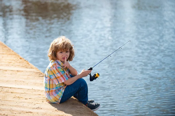 Serious, little boy child is fishing on the river with a fishing rod. — Stock Photo, Image