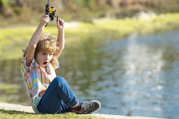 Un ragazzo bambino pescatore si trova nel fiume con una canna da pesca e cattura il pesce. — Foto Stock