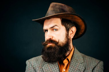 Geçmişi olan yakışıklı bir adam, siyah arka planda ciddi sakallı bir hippinin portresi..