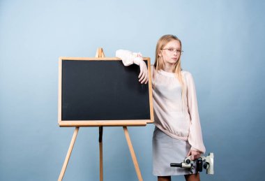 Genç kız öğrenci. Mikroskop tutan çekici küçük bir kız. Tahtanın yanındaki modern liseli kızın portresi.