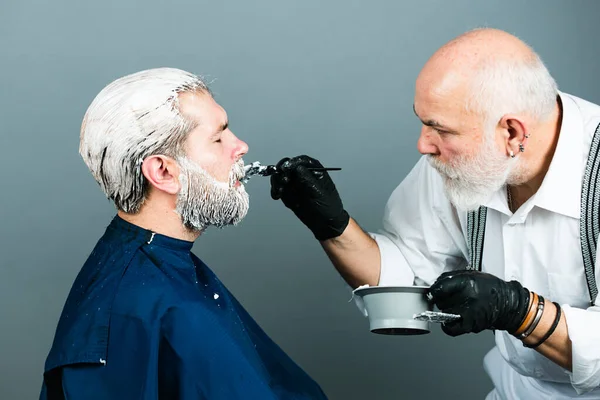 Homem estilista com tintura de cabelo e cabelo escova para colorir no salão. Processo de um cara ter seu cabelo tingido no cabeleireiro. — Fotografia de Stock