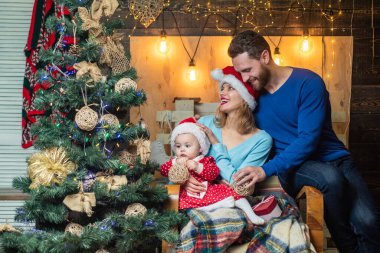 Arka planda sevimli ebeveynler var. Neşeli şirin bebek Noel hediyesini açıyor. Mutlu aile için Noel.