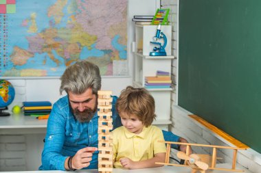 Anaokulu eğitimi. Okulda öğrencilere destek oluyor. Baba ve oğul birlikte okuyorlar. Baba ve oğul evde Jenga oynuyorlar..