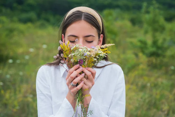 Retrato de una hermosa joven en primavera. Mujer joven sosteniendo ramo de flores silvestres en la naturaleza. Concepto de primavera. —  Fotos de Stock