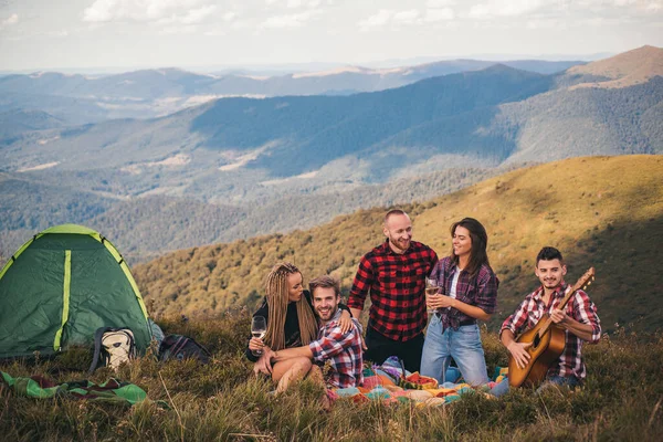 友人のグループが一緒に山の上に座っている。休日に屋外で楽しむ若者たち。幸せな友人たちは山を見て一緒に楽しんでいます。旅行キャンプのコンセプト. — ストック写真