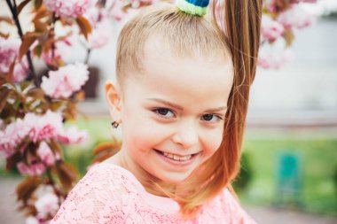 Çiçek açan ağaçlarda açık havada komik bir kız portresi. Komik genç kızın yüz resmi..