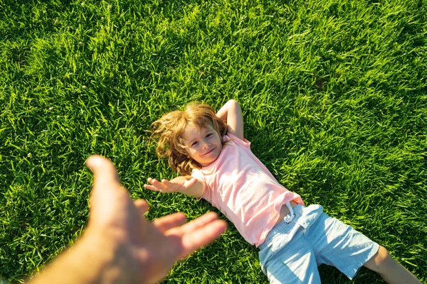 Boy pull father hand. Follow me, hand-in-hand walking on sunny day. Kid holding mans hand and leading him on nature outdoor.