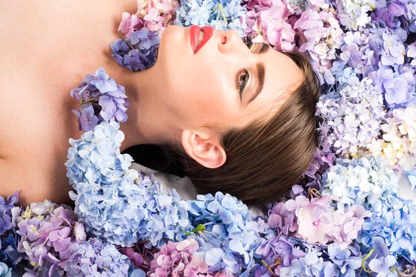 Schönheit Frau auf Blumen liegend. Blossom Make-up Kosmetik und Hautpflege. Mädchen mit Hortensienblüten. — Stockfoto