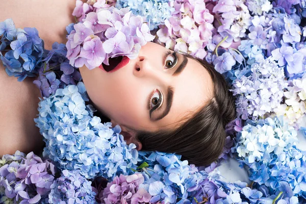 Schönheit der Natur. Frau auf Blumen liegend. Einheit mit der Natur. Blühen. Make-up Kosmetik und Hautpflege. Mädchen mit Hortensienblüten. — Stockfoto