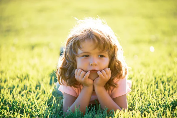 Niño en el parque al aire libre. Chico de primavera acostado en la hierba. Caminata de verano. Adaptación infantil. —  Fotos de Stock