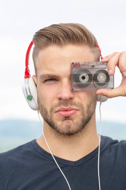 Kaset ve kulaklıkla müzik dinleyen bir adam. Duygusal portre adamı. Retro oynatıcı. 90 'ların tarzında genç sakallı bir adam..
