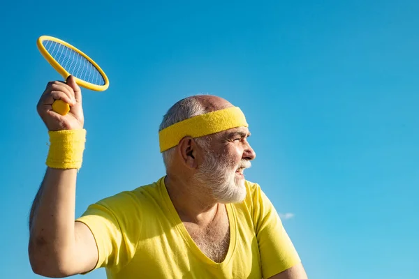 Älterer Mann beim Tennisspielen vor blauem Himmel. Tennisprofi beim Aufschlag. — Stockfoto