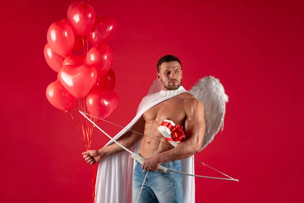 Ángel de San Valentín. Hombre sexy con alas de ángeles. Flecha de amor, Cupido, Amor. 14 de febrero. Aislado sobre rojo. — Foto de Stock