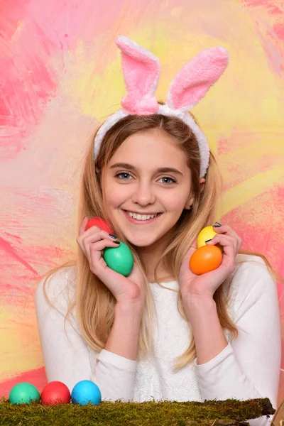 Mujer disfrazada de conejo de Pascua con orejas y huevos. Mujer mirando por encima de una superficie. —  Fotos de Stock