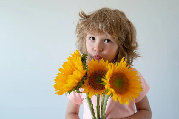 Улыбающийся ребенок с подсолнухами. Счастливый ребенок с букетом цветов. Симпатичный милый мальчик романтический и сюрприз. — стоковое фото