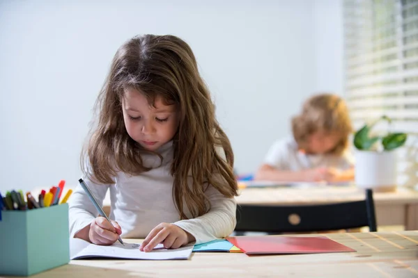 Barn i klassrummet i skolan. Utbildning, grundskola, lärande och människor koncept - grupp av skolbarn med pennor och anteckningsböcker skriva. — Stockfoto