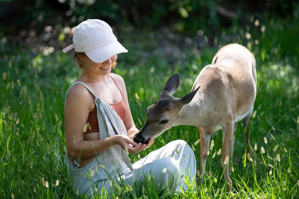 Eenheid met de natuur. Meisjes voeren bambi herten. Het concept wilde dieren. Vrouw die fawn voedt. Dier in het park. — Stockfoto